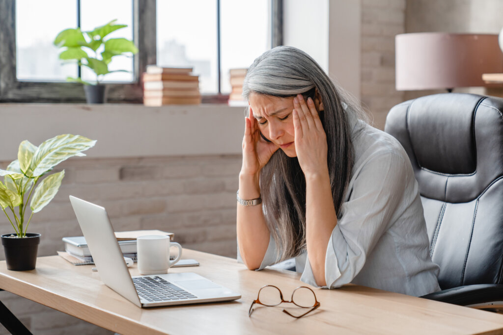 A woman experiencing a migraine while at work at her desk