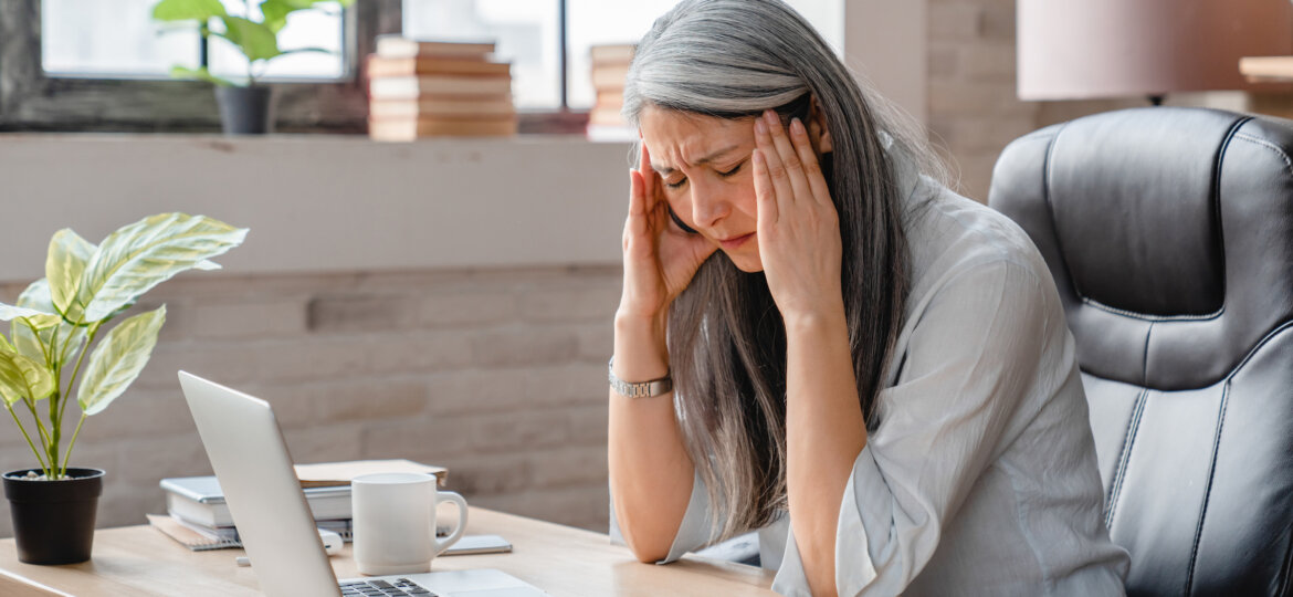 A woman experiencing a migraine while at work at her desk