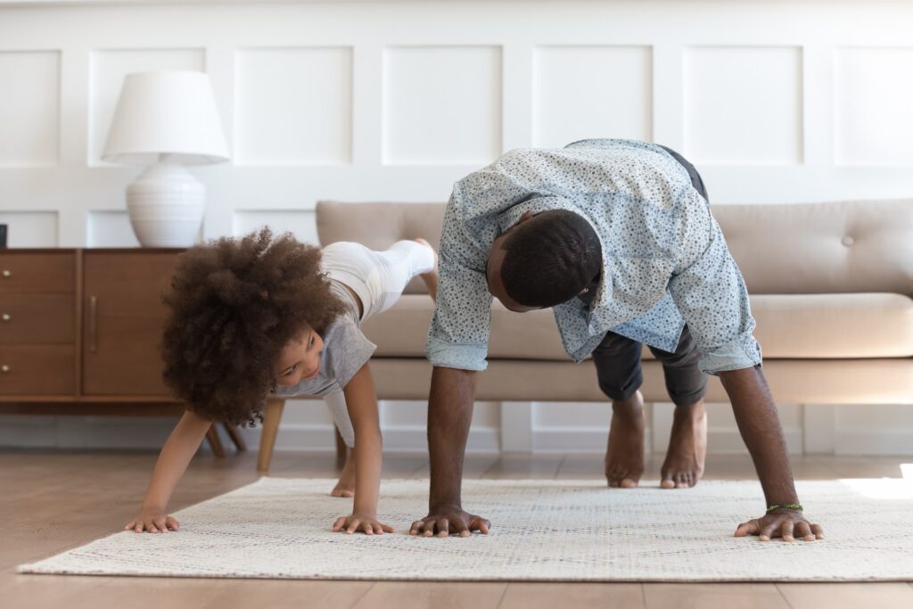 African father and small daughter in casual clothes do pushup pressup exercise on carpet on warm floor in living room, sporty lifestyle, getting physically stronger, have fun, pastime with kid concept