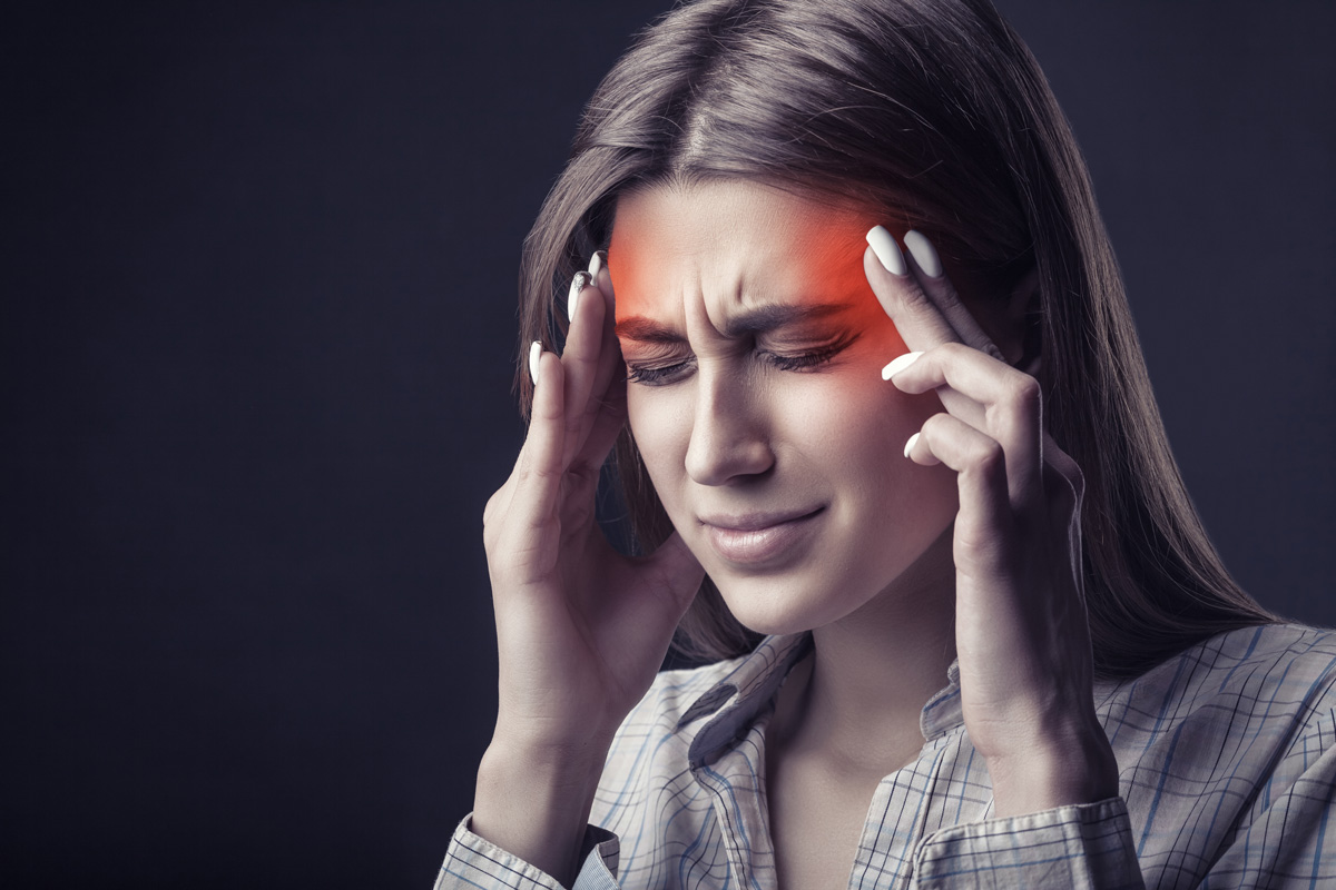 A woman with a migraine touching her head in El Paso.