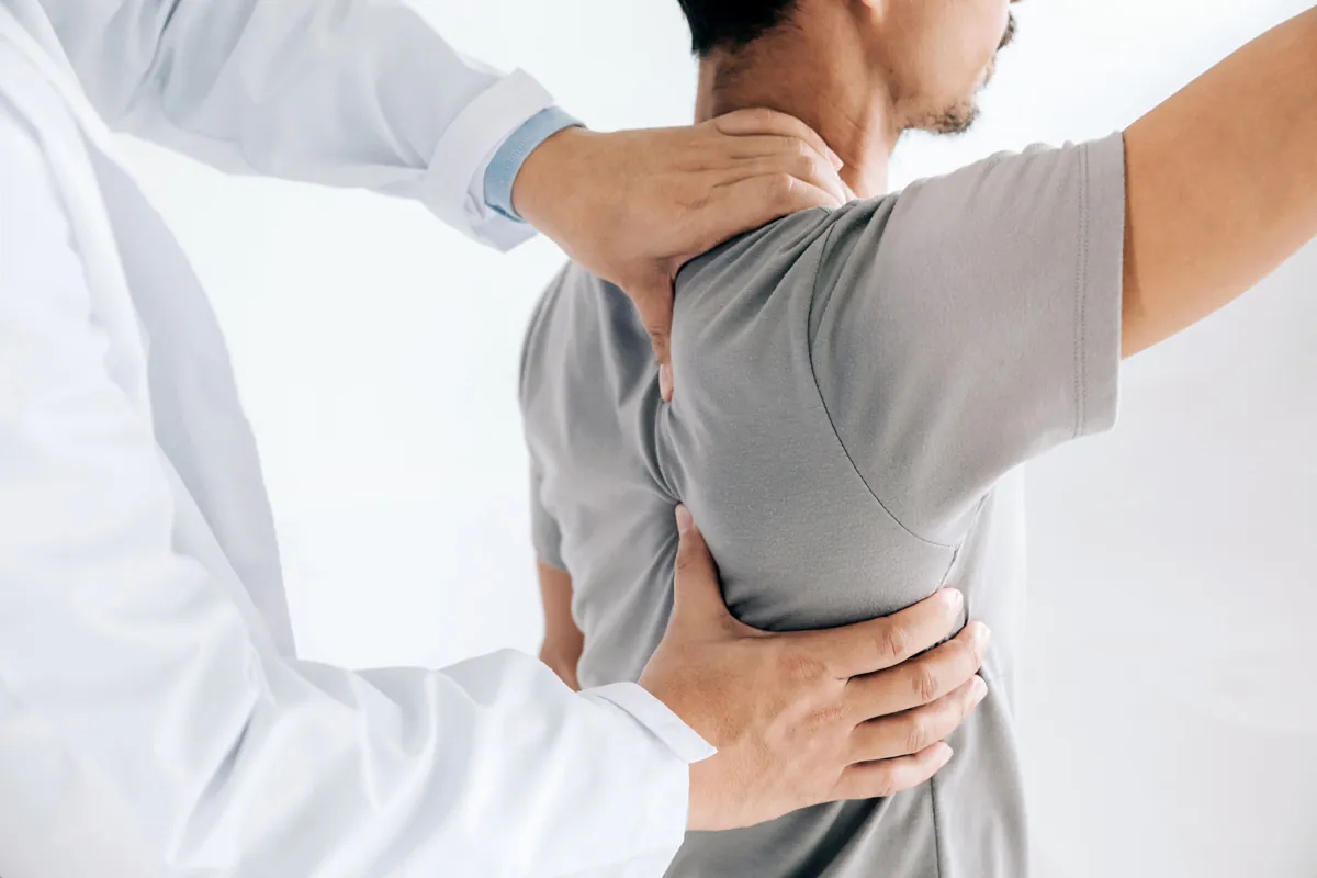 A physical therapist holding a person’s shoulder while they lift up their arm in El Paso.